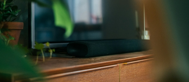 Nærbillede af en elegant, mørk soundbar på et træmøbel.