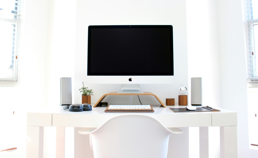 Minimalistisk skrivebord med hvide højttalere Et moderne hvidt interiør med et skrivebord med en computer og to højttalere på hver side